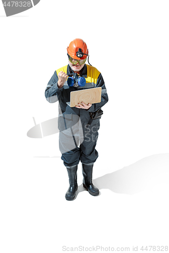 Image of The studio shot of senior bearded male miner standing at the camera on a white background.