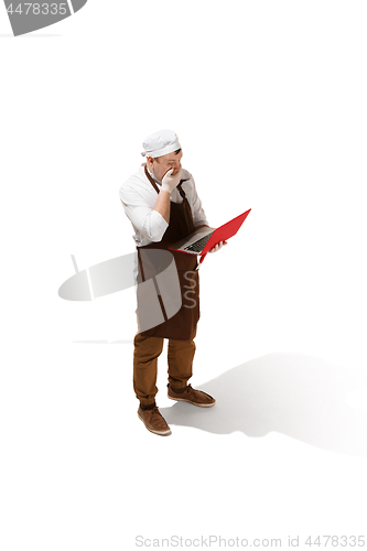 Image of Serious butcher posing with a laptop isolated on white background