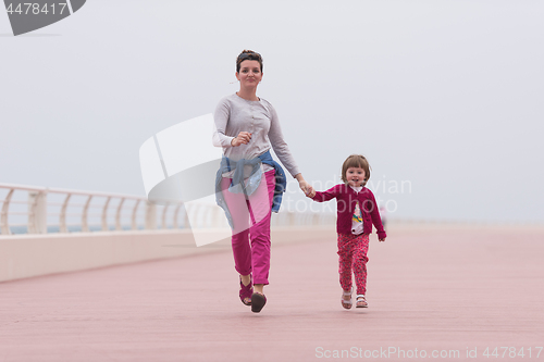 Image of mother and cute little girl on the promenade by the sea