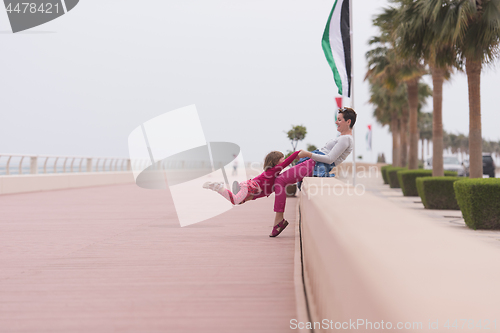 Image of mother and cute little girl on the promenade by the sea