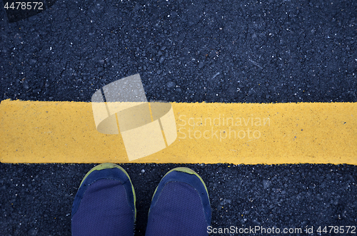 Image of Standing on asphalt ground with yellow line