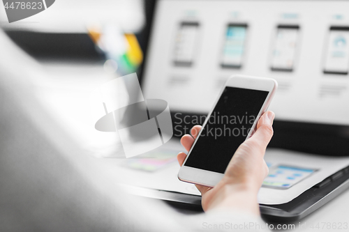 Image of web designer with smartphone and laptop at office