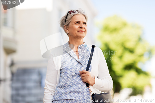 Image of happy senior woman on city street in summer