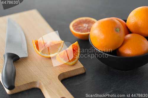 Image of close up of oranges and knife on cutting board