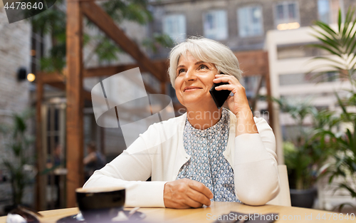Image of senior woman calling on smartphone at street cafe