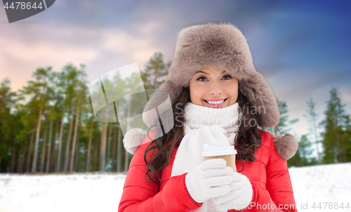 Image of woman in fur hat with coffee over winter forest