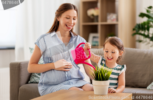 Image of pregnant mother and daughter watering home plant