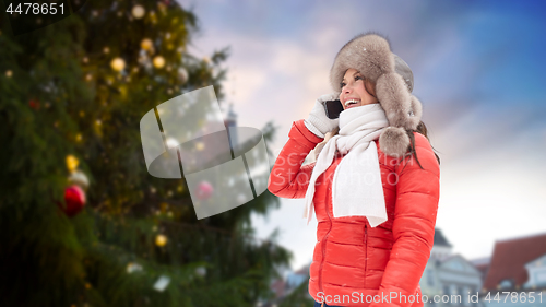 Image of woman calling on smartphone over christmas tree