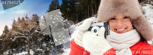 Image of happy woman with film camera over winter forest