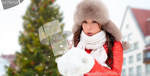 Image of woman blowing to snow over christmas tree