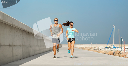 Image of couple in sports clothes running outdoors