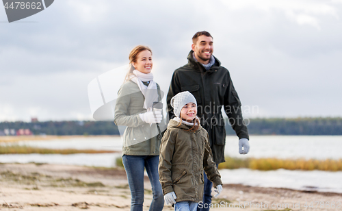 Image of happy family walking along autumn beach