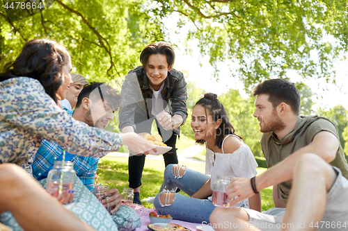 Image of friends with drinks and food at picnic in park