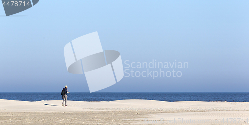 Image of Old male photographer walking on the beach