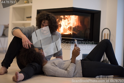 Image of multiethnic couple using tablet computer on the floor