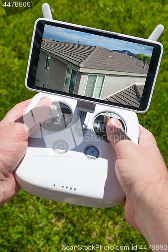 Image of Hands Holding Drone Quadcopter Controller With Residential Roof 