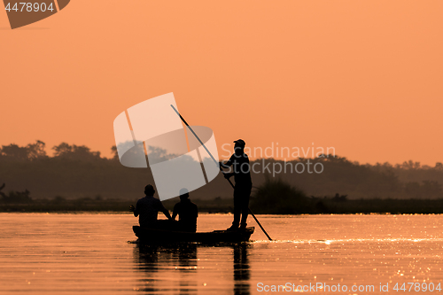 Image of Men in a boat on a river silhouette