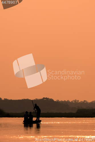 Image of Men in a boat on a river silhouette