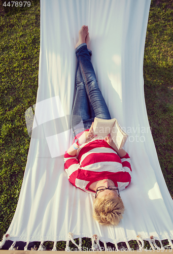 Image of woman reading a book while relaxing on hammock