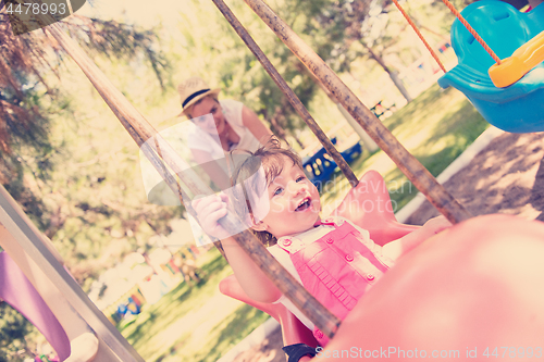 Image of mother and daughter swinging in the park
