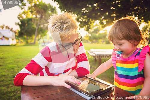 Image of mom and her little daughter using tablet computer