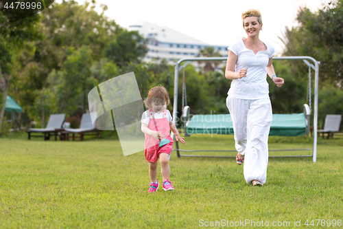 Image of mother and little daughter playing at backyard