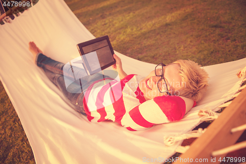 Image of woman using a tablet computer while relaxing on hammock