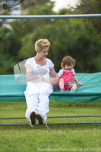 Image of mother and little daughter swinging at backyard