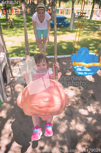 Image of mother and daughter swinging in the park