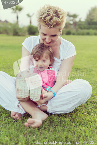 Image of mother and little daughter playing at backyard