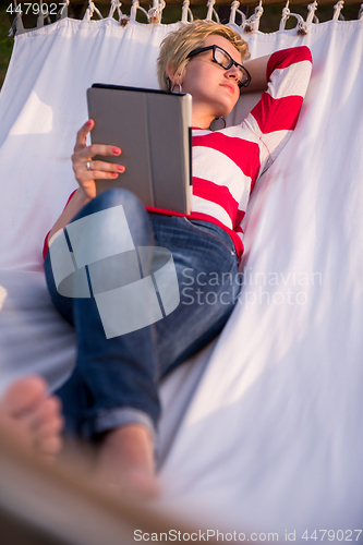 Image of woman using a tablet computer while relaxing on hammock