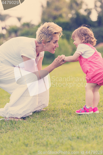 Image of mother and little daughter playing at backyard