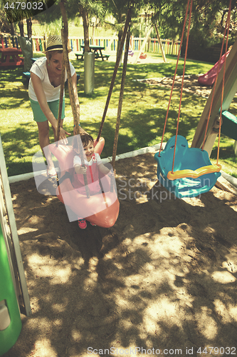 Image of mother and daughter swinging in the park