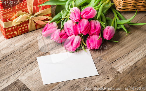 Image of Beautiful bouquet from pink tulips and a gift on a table