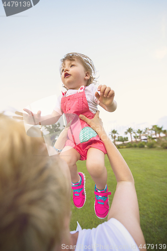 Image of mother and little daughter playing at backyard