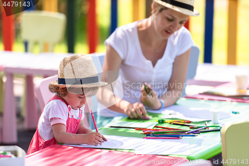 Image of mom and little daughter drawing a colorful pictures