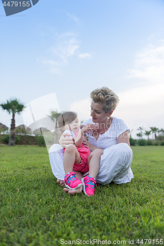 Image of mother and little daughter playing at backyard