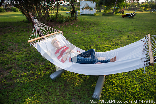 Image of woman reading a book while relaxing on hammock