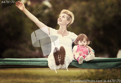 Image of mother and little daughter swinging at backyard