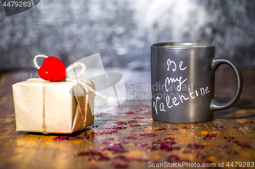 Image of Valentine's day concept with black cup, chalk inscription on a mug and a red heart