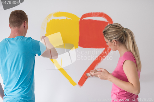 Image of couple are painting a heart on the wall