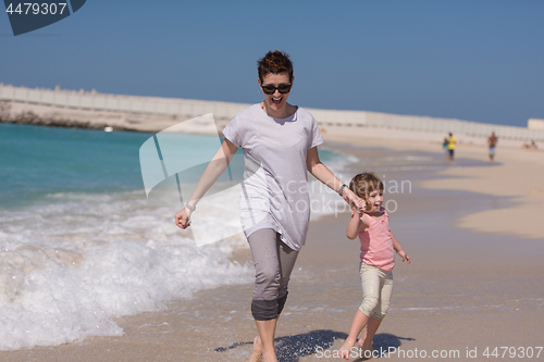 Image of mother and daughter running on the beach