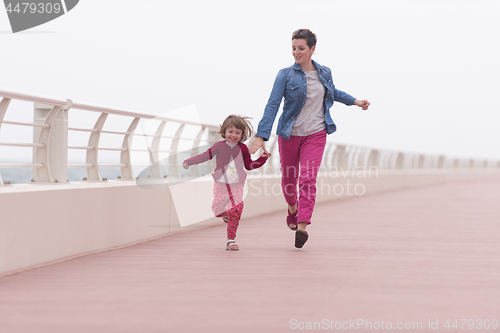 Image of mother and cute little girl on the promenade by the sea