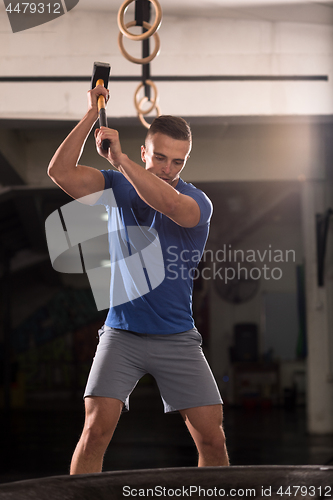 Image of man workout with hammer and tractor tire