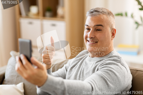 Image of man having video chat on smartphone at home