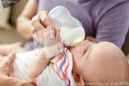 Image of close up of father feeding baby from bottle