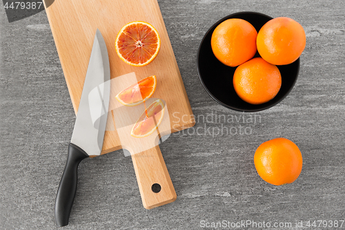 Image of close up of oranges and knife on cutting board