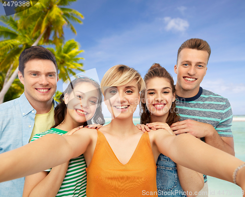 Image of happy friends taking selfie over tropical beach