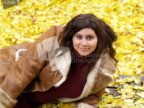 Image of young plus-size model with yellow fall leaves and jacket