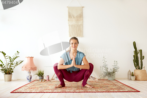 Image of young woman doing garland pose at yoga studio
